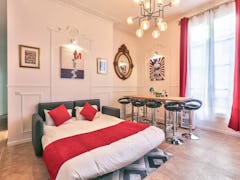 This Mickey Mouse-themed Airbnb in Paris has a leather pullout couch with red throw pillows, a big w...