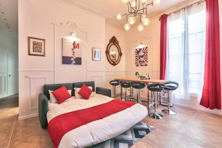 This Mickey Mouse-themed Airbnb in Paris has a leather pullout couch with red throw pillows, a big w...