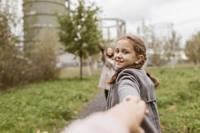 A young girl pulls the person behind the camera out into a field