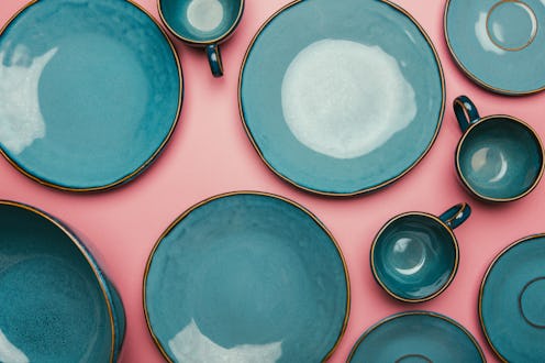 A series of empty blue ceramic plates on a pink background.  Intermittent fasting, where food is res...