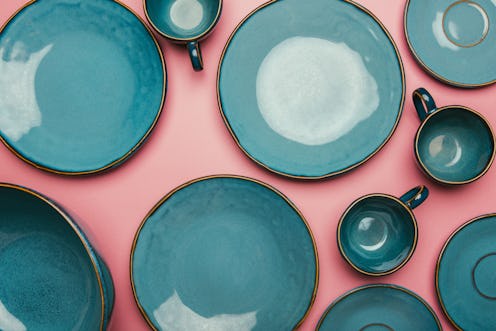 A series of empty blue ceramic plates on a pink background.  Intermittent fasting, where food is res...