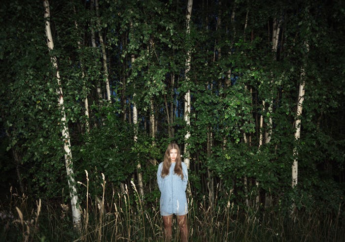 Woman standing alone in woods