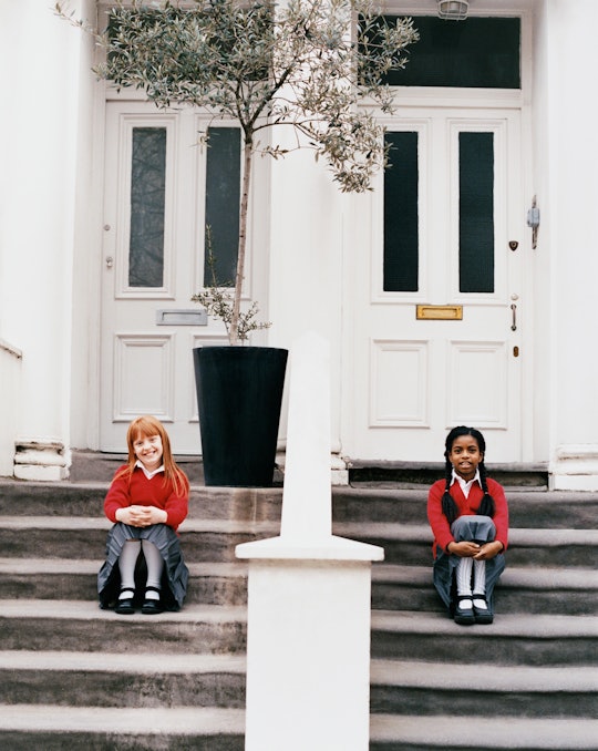 Two girls sit on adjacent stoops in front of their houses