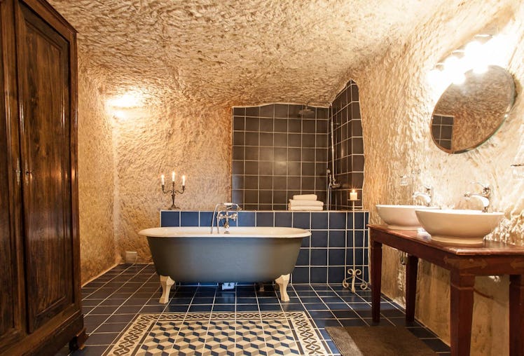 A blue bathtub sits in the center of a blue tiled bathroom in a cave home on Airbnb. 