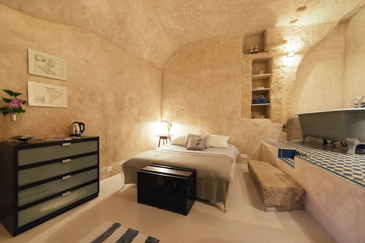 A bed and vintage bathtub are all in one cozy room in a cave home on Airbnb. 