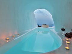 Candles and wine surround a jacuzzi in a cave home in Santorini on Airbnb. 