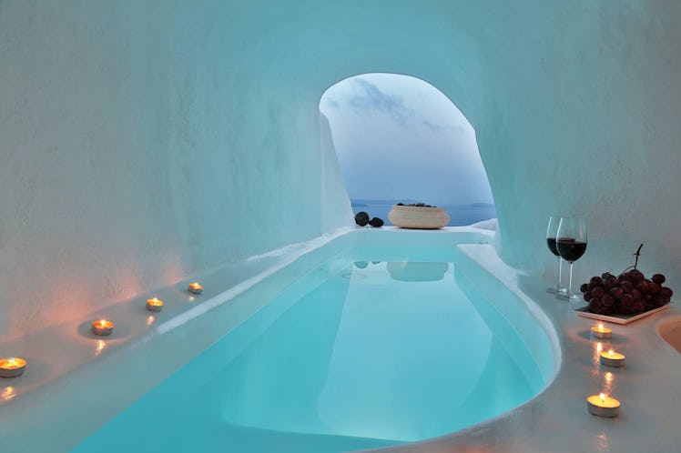 Candles and wine surround a jacuzzi in a cave home in Santorini on Airbnb. 