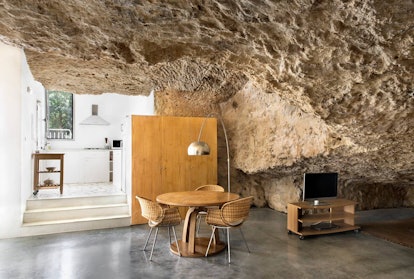 A dining table and TV both fill up the space in an open cave home on Airbnb. 