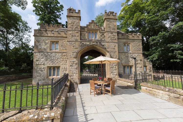 A table sits outside of the castle gatehouse listed on Airbnb with chairs and an umbrella. 