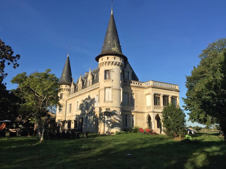 Trees, chairs, and greenery surround a beautiful castle that's listed on Airbnb in France. 