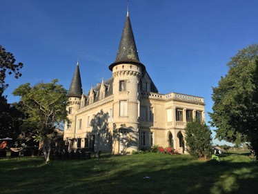 Trees and green grass surround a beautiful castle that's listed on Airbnb in France. 
