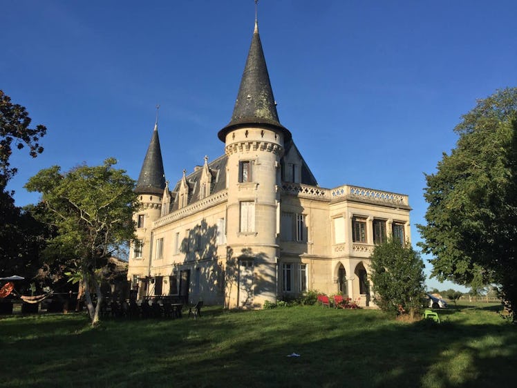 Trees and green grass surround a beautiful castle that's listed on Airbnb in France.
