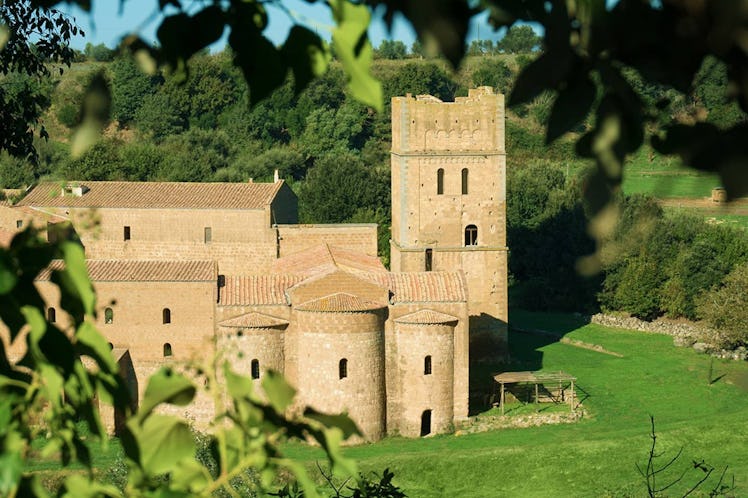 A medieval castle in Italy that's listed on Airbnb is surrounded by greenery.