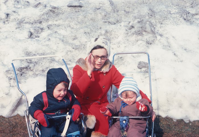 A vintage mother with two children in strollers in front of snow