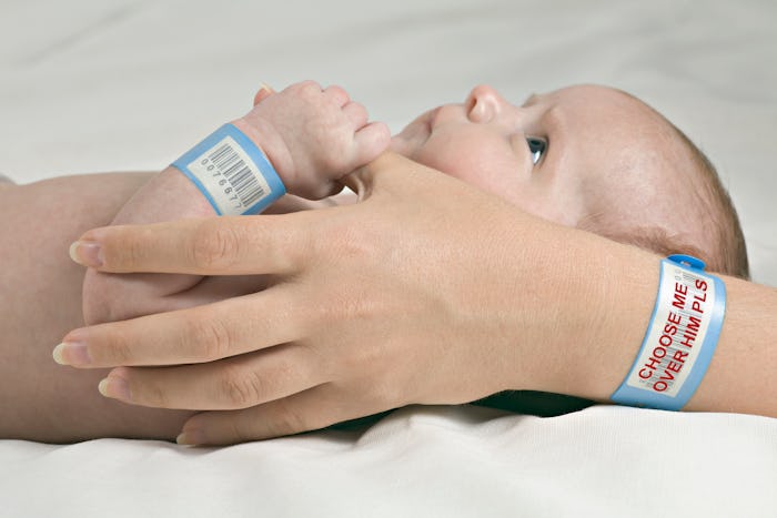 a mother's hands hold a newborn with hospital bracelets on