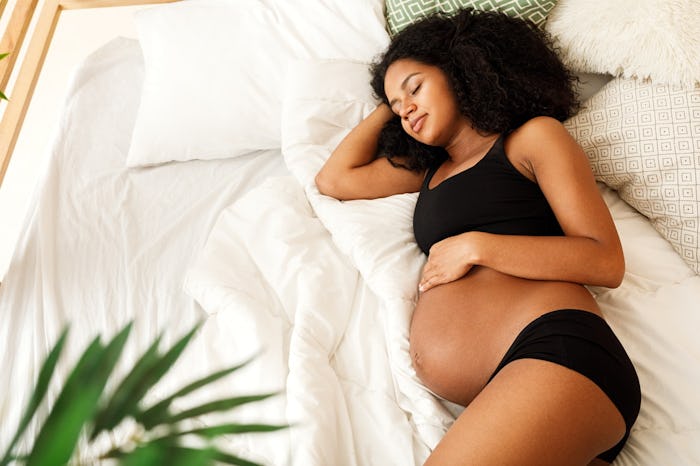 A pregnant woman in comfortable maternity underwear resting on her bed