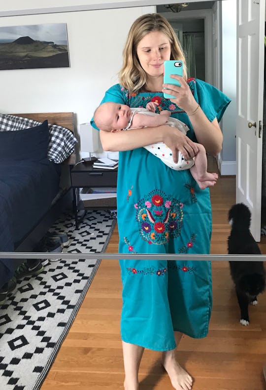 A mother in blue dress holds her newborn baby in living room