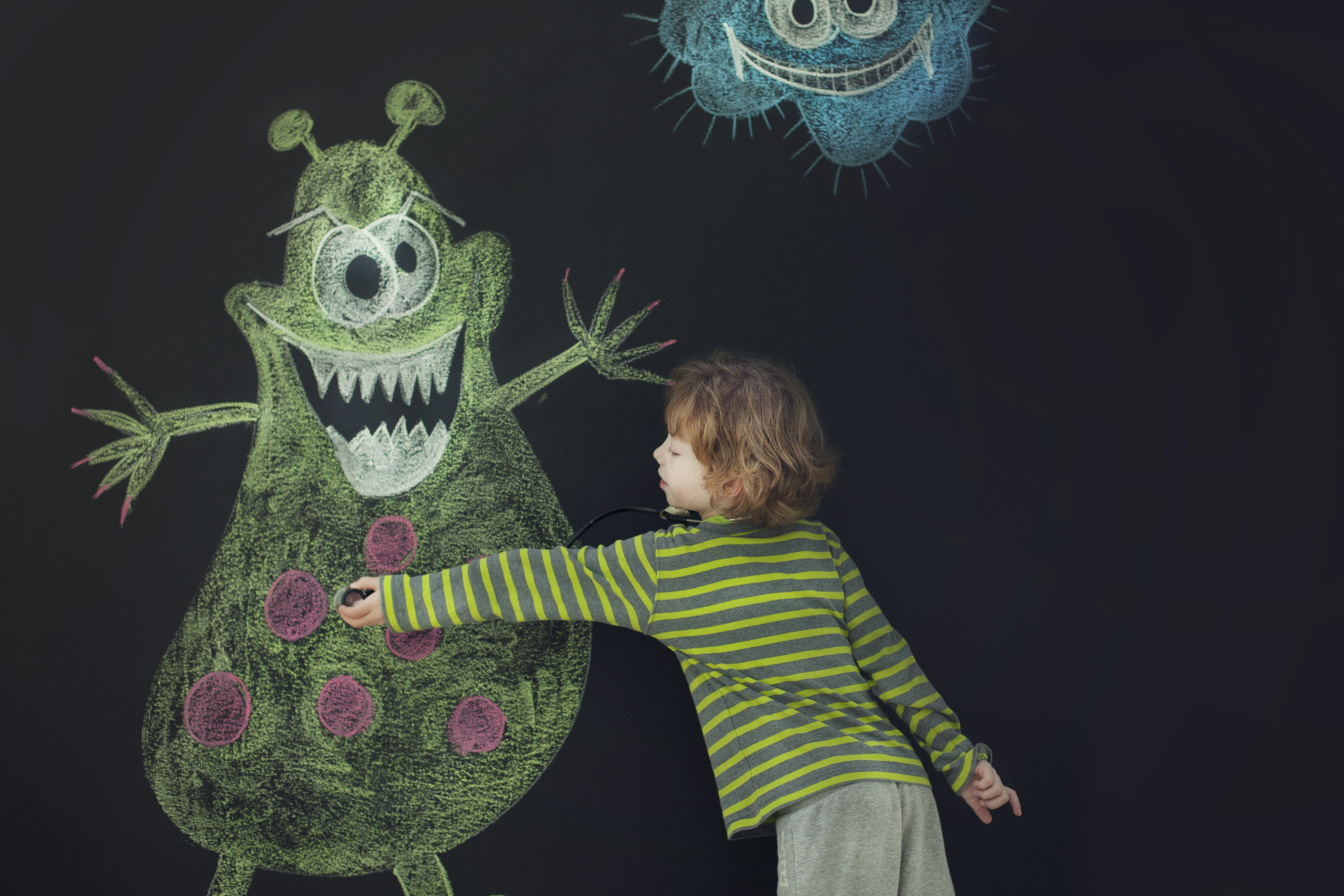 boy drawing monster on chalkboard