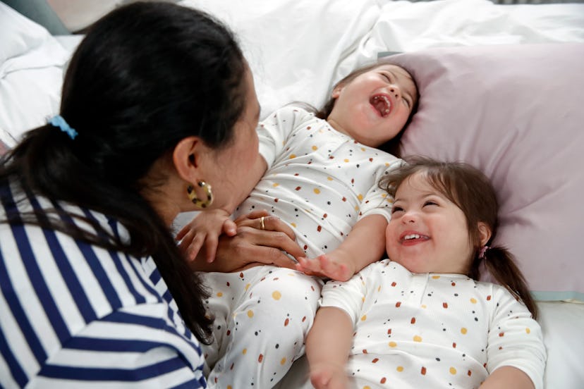 Identical twin girls with Downs syndrome laughing with their mother