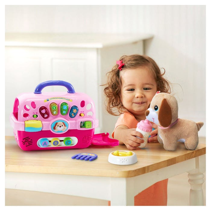 a toddler girl playing with a vtech care for me learning carrier