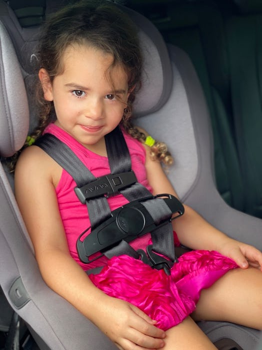 A young girl smiles in her car seat, equipped with the Car Seat CoPilot hot car safety device.
