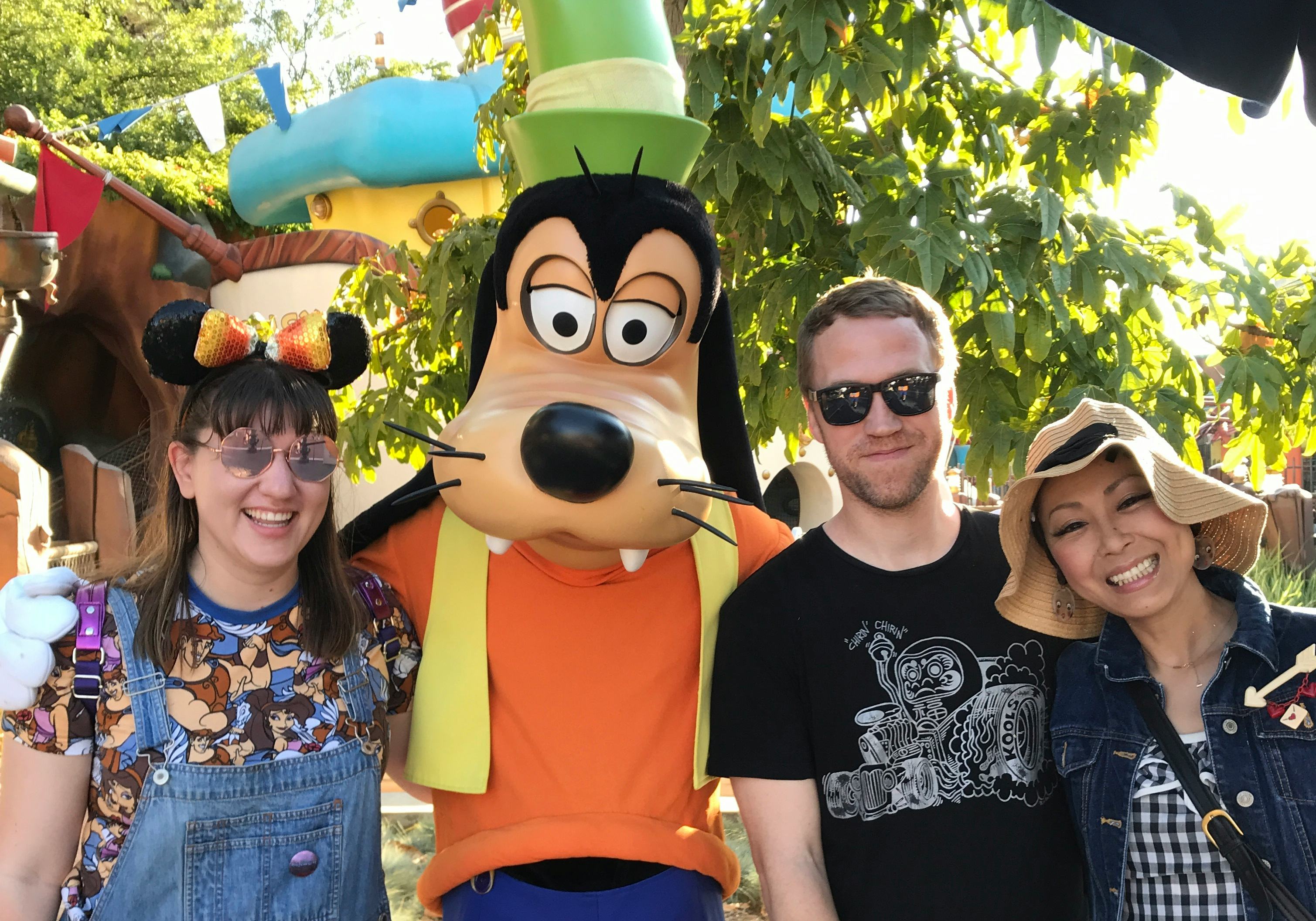 A group of friends poses for a picture with Goofy at Disneyland. 