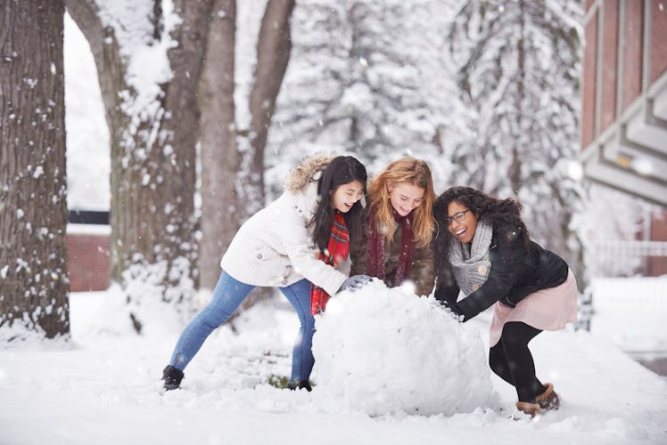 Multi-ethnic female friends building snowman