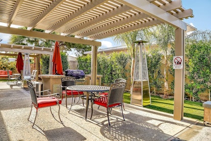 A outdoor table and chairs with a grill sit in the backyard of a Palm Springs Airbnb.