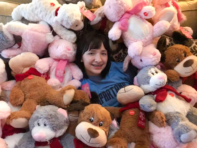 A picture of a smiling girl amidst a sea of plush toys.