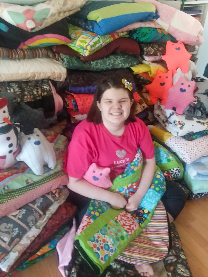 A picture of a smiling girl surrounded by quilts.