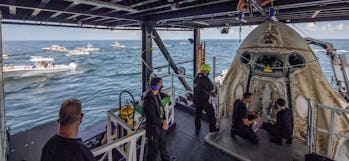 Onlookers watch SpaceX's recovery team open the hatch to the Crew Dragon spaceship.