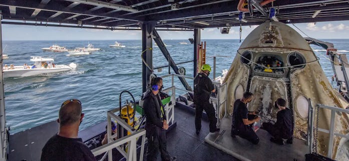 Onlookers watch SpaceX's recovery team open the hatch to the Crew Dragon spaceship.