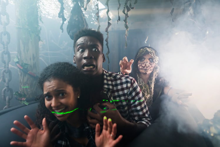 Young man & woman in haunted house on Halloween with zombie