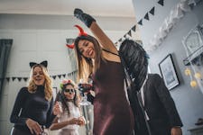 Young woman partying in devil's costume on Halloween before posting on Instagram with a clever capti...
