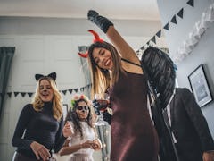 Young woman partying in devil's costume on Halloween before posting on Instagram with a clever capti...