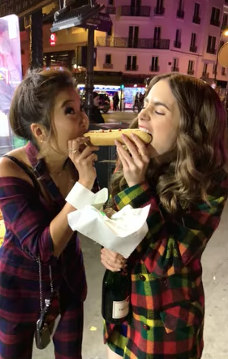 Emily (Lily Collins) and Mindy (Ashley Park) bite out of a hot dog at the same time like in 'Lady an...