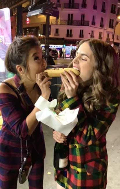 Emily (Lily Collins) and Mindy (Ashley Park) bite out of a hot dog at the same time like in 'Lady an...