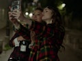Emily (Lily Collins) and Mindy (Ashley Park) pose for a selfie in Paris at night. 