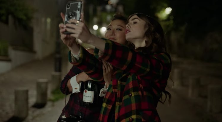 Emily (Lily Collins) and Mindy (Ashley Park) pose for a selfie in Paris at night. 