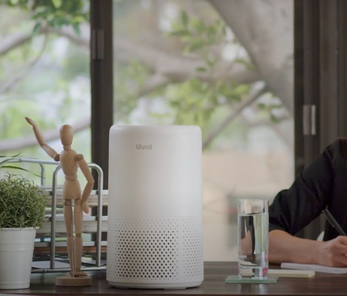 A woman sits at a desk with a Levoit Air Purifier