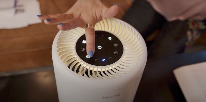 Hand pressing button on Levoit air purifier