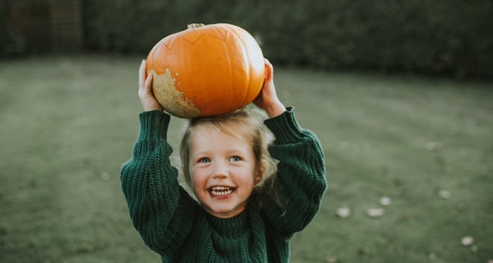 happy kid holding pumpkin from pumpkin patch; this is the best time to go pumpkin picking