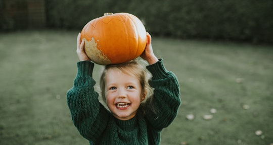 happy kid holding pumpkin from pumpkin patch; this is the best time to go pumpkin picking
