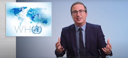 John Oliver in a suit speaking with the logo of the World Health Organization next to him