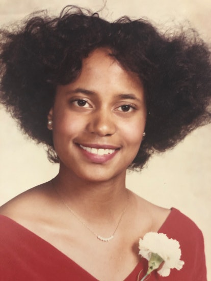 A portrait of Elaine Witter in a red V-neck dress and a white flower, and pearl earrings 