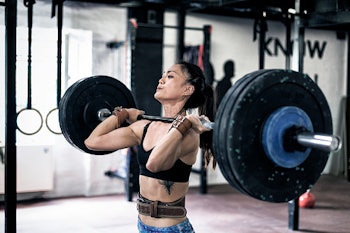 A woman in gym attire powerlifting while practicing intermittent fasting