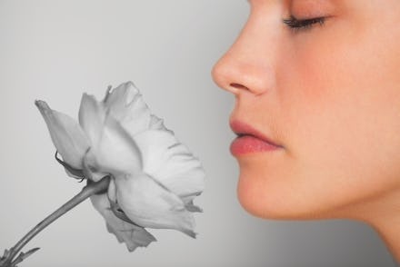 Close up of a girl trying to smell a grey, colorless flower, as she lost her sense of smell due to c...