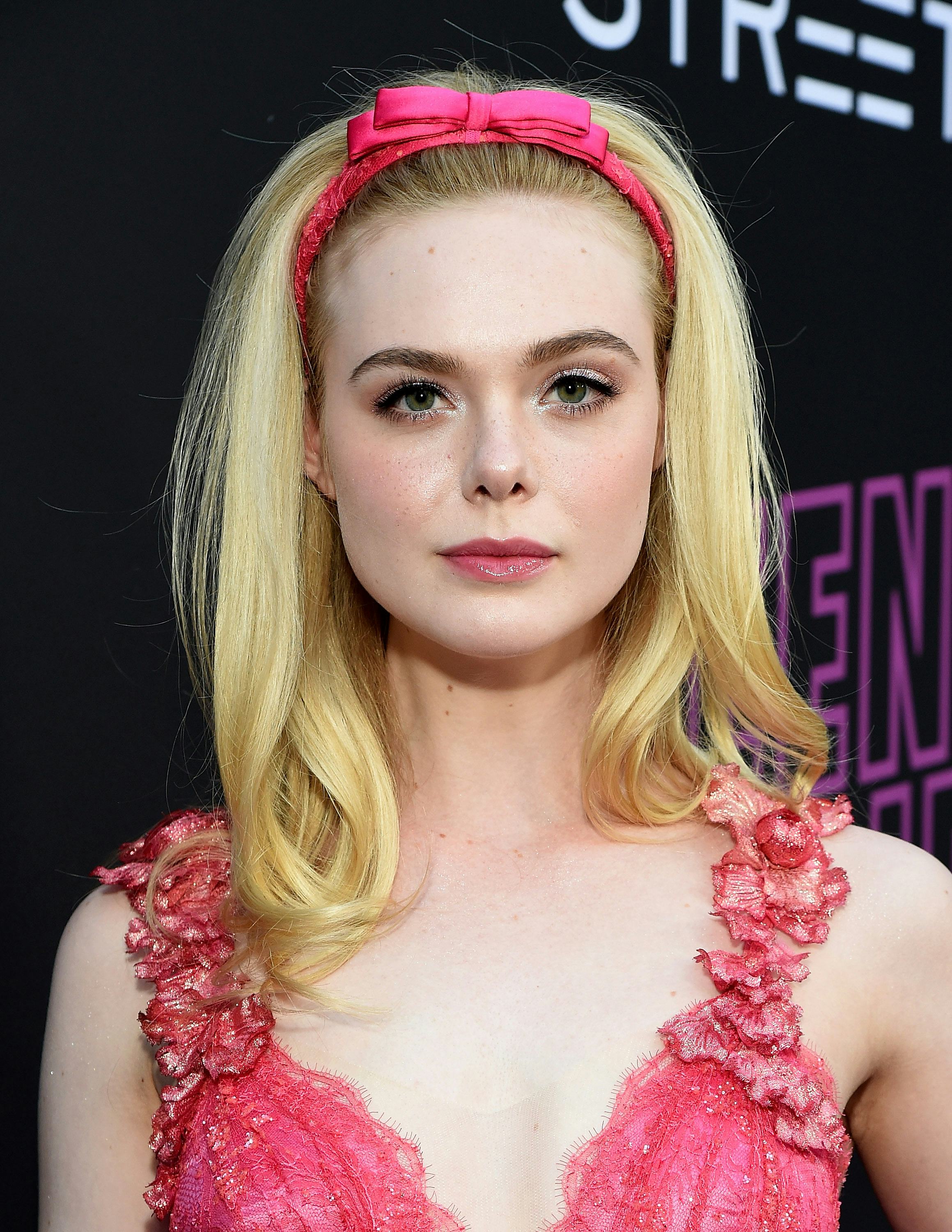  Elle Fanning on the red carpet in a pink tulle gown with flowers on the straps and a headband with ...