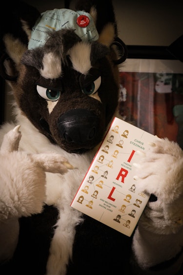 A furry holding a copy of IRL.