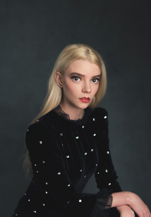 Anya Taylor-Joy in a black velvet sequin shirt, sitting down with her hands crossed 